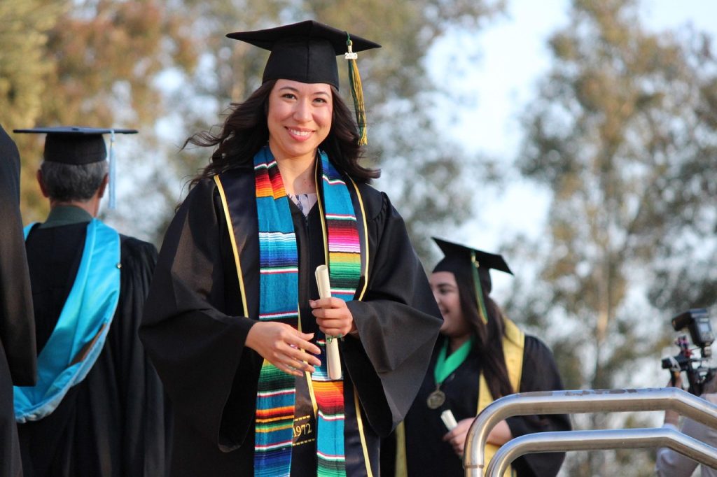 A smiling graduate in cap and gown with a colorful stole