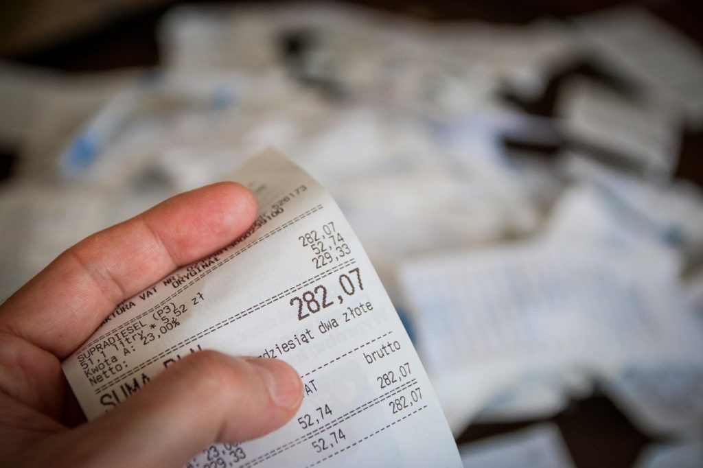 A hand holding a long itemized receipt