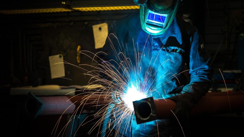 A welder in a protective helmet working as sparks fly